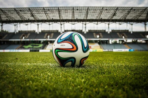 Voetbalwedstrijd in een stadion met een tablet waarop voetbalstatistieken, schoten en expected goals worden geanalyseerd.