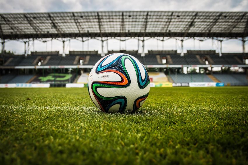 Voetbalwedstrijd in een stadion met een tablet waarop voetbalstatistieken, schoten en expected goals worden geanalyseerd.